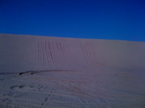 2005 Dodge 1500 - Tire tracks mark the sandy slopes of dunes under a bright blue sky.