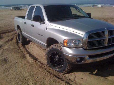 2005 Dodge 1500 - This silver Dodge 1500 pickup truck is seen on a sandy beach, equipped with aftermarket wheels and tires.