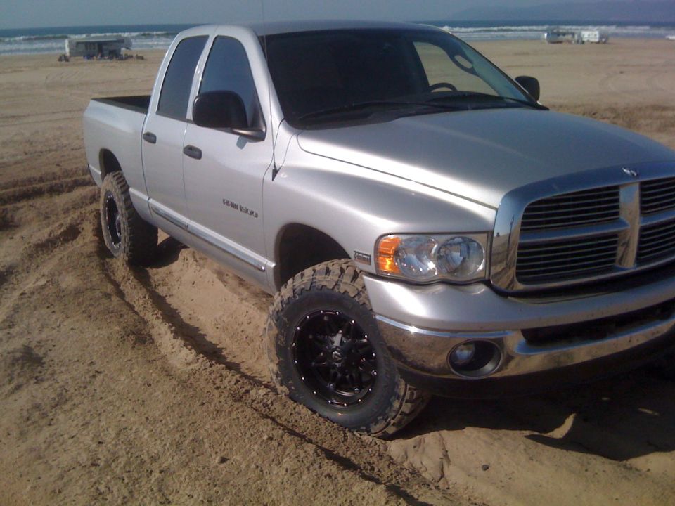 Silver 2005 Dodge 1500 pickup truck on beach with aftermarket wheels