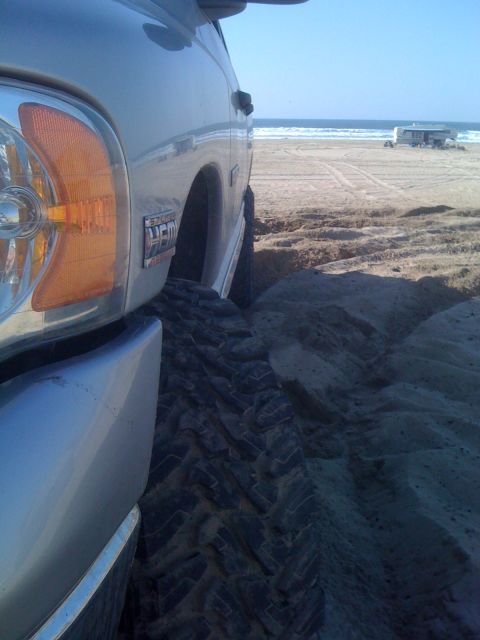 2005 Dodge 1500 - A 2005 Dodge 1500 is stuck in the sand with the ocean in the background.