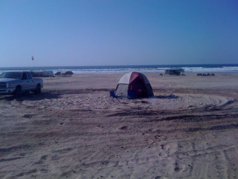 2005 Dodge 1500 - A silver 2005 Dodge 1500 pickup truck is seen parked on a beach with a tent and the ocean in the background.