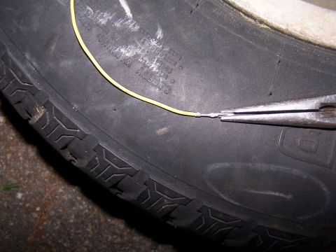 1973 Ford Bronco - A close-up shows a yellow wire being repaired on the sidewall of a tire.