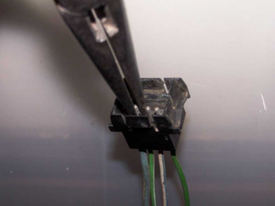 Wiring harness connector with pliers gripping pins, green and white wires attached
