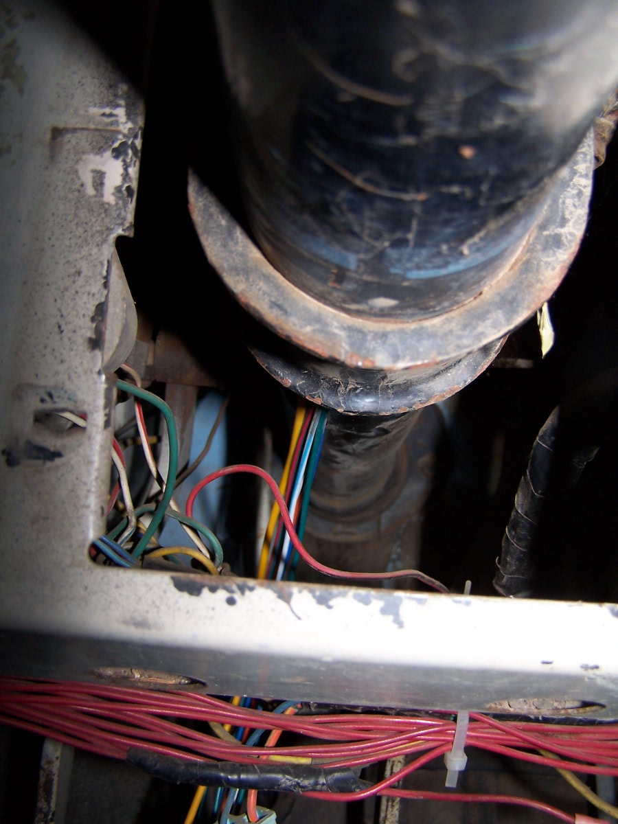 Close-up of a messy vehicle wiring harness with many colored wires and a large black conduit