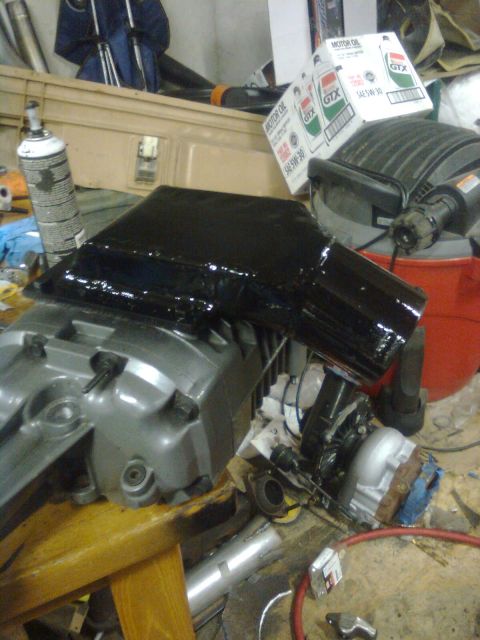 1984 Ford Bronco - A close-up view of an engine part with a newly installed black intake manifold, likely for a supercharger setup.