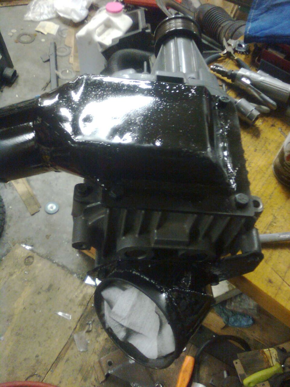 Painted differential housing with a paper towel stuffed in one end, resting on a workbench