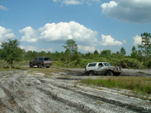 1992 Ford Bronco - Two SUVs are stuck in the mud, with one attempting to tow the other.
