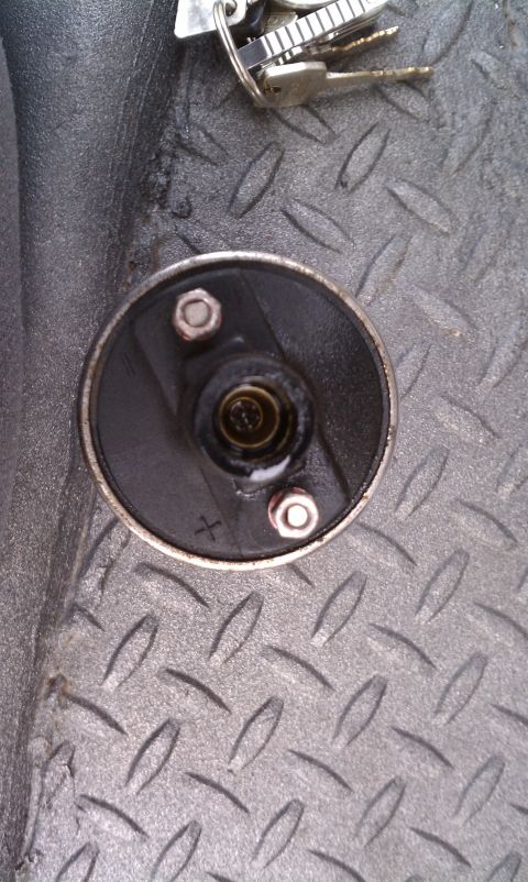 1979 Ford Bronco - A close-up view of a vehicle's distributor cap, with a set of keys resting nearby on a textured metal surface.