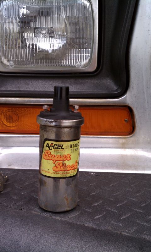 1979 Ford Bronco - An Accel ignition coil is shown in front of a vehicle's front end, with the headlight and turn signal visible.