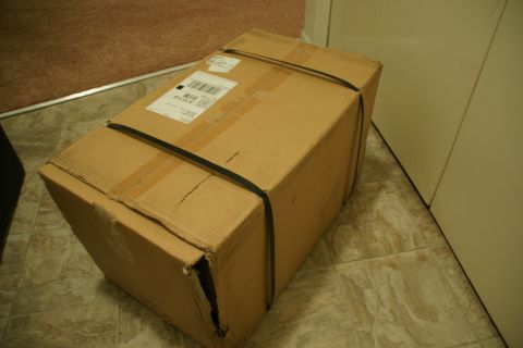 1995 Ford Taurus - A cardboard box with a shipping label and straps is shown on a tiled floor.