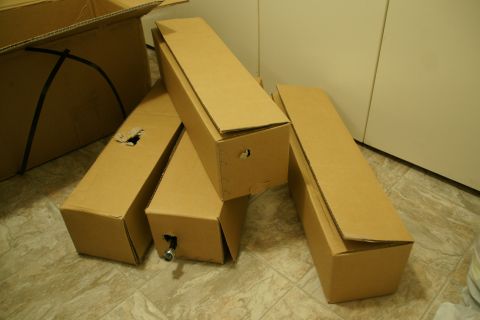 1995 Ford Taurus - Several cardboard boxes, likely containing automotive parts, are stacked on a tiled floor.