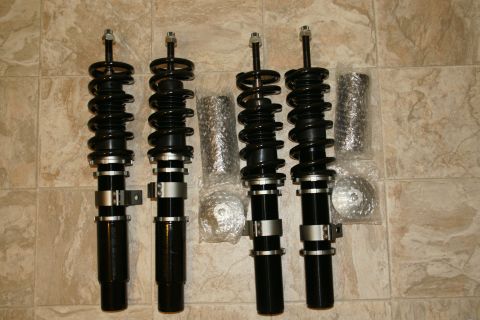 1995 Ford Taurus - Set of four adjustable coilovers, likely aftermarket performance parts, laid out on a tiled surface.