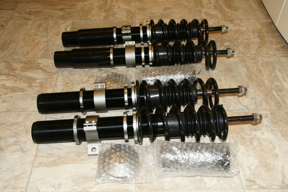 Four black coilover suspension assemblies with silver adjustable collars