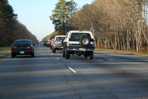 1982 Ford Bronco - Multiple vehicles, including a 1982 Ford Bronco, travel down a highway on a clear day.