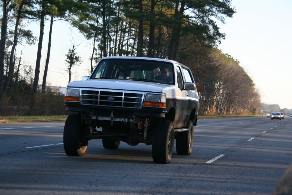 White and black Ford Bronco, 1992 model year, driving on a highway
