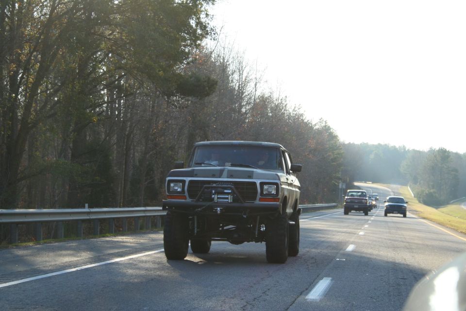Lifted pickup truck with winch on front bumper driving on highway. Other cars in distance