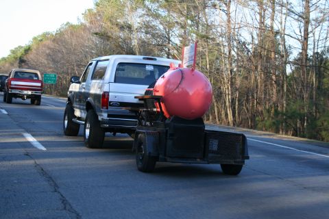 1982 Ford Bronco - A silver SUV, likely a 1992 Ford Bronco, is seen on the highway towing a large red smoker on a trailer.