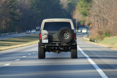 1982 Ford Bronco - This 1982 Ford Bronco is seen from behind while driving on a highway with other vehicles in the distance.