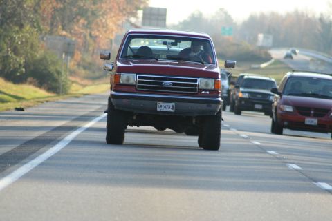 1982 Ford Bronco - A red 1987 Ford F-150 pickup truck is seen driving on a highway with other vehicles.
