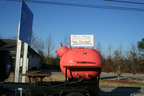 1982 Ford Bronco - A large, red, pig-shaped smoker sits on a trailer under a bright blue sky.
