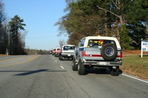 1982 Ford Bronco - Several Ford Broncos drive down a highway on a clear day.