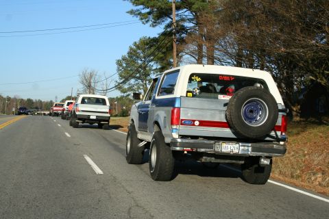 1982 Ford Bronco - Several Ford Broncos are driving in a convoy on a sunny day.