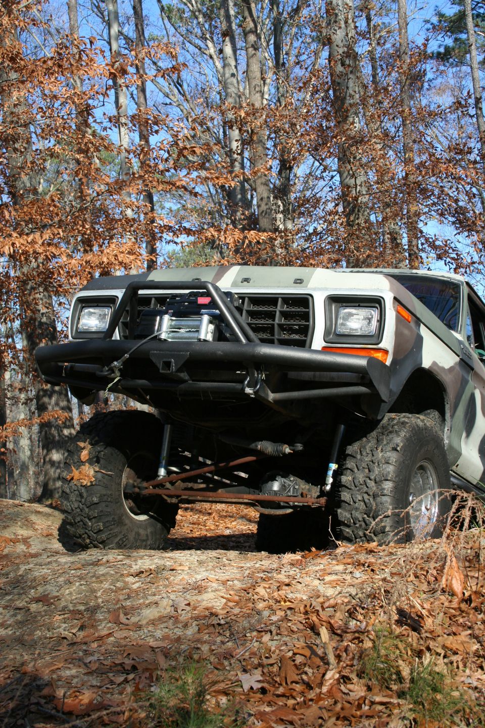 Modified Ford Bronco with custom bumper and camouflage paint, front view off-road