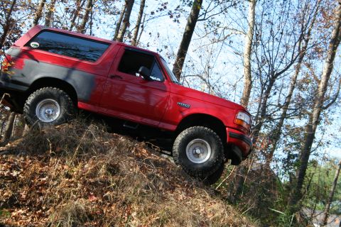 1982 Ford Bronco - This red Ford Bronco is navigating a steep, wooded incline.