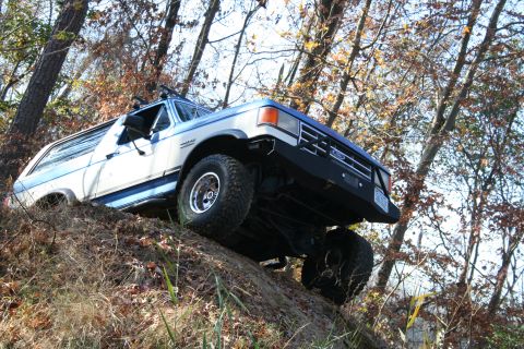 1982 Ford Bronco - This Ford Bronco is navigating a steep, wooded incline, its off-road capabilities.