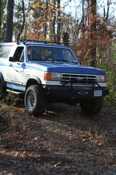 1982 Ford Bronco - This Ford Bronco is parked off-road, showing its custom bumper and roof rack. The license plate is visible.