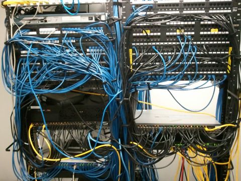 1985 Ford F-150 - A server rack is filled with a chaotic tangle of blue and yellow network cables.