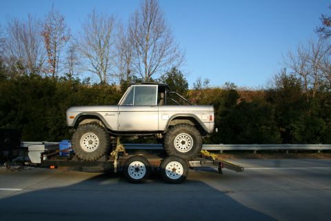 1982 Ford Bronco - A silver 1982 Ford Bronco is transported on a trailer, its classic body style and off-road tires.