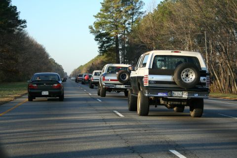 1982 Ford Bronco - A line of vehicles, including a two-tone Ford Bronco, travels down a highway on a clear day.