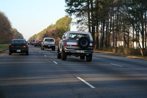1982 Ford Bronco - A Ford Bronco drives down a highway, with other vehicles visible in the distance.