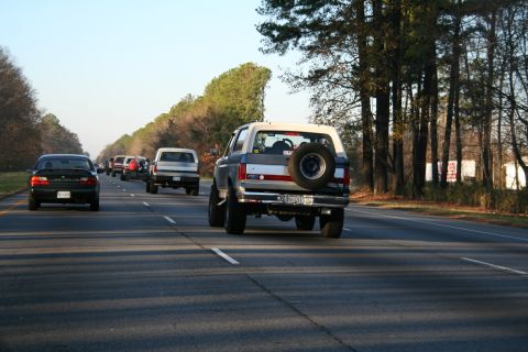 1982 Ford Bronco - A 1980s Ford Bronco, possibly a 1982 model, is seen on the highway with a spare tire mounted to its rear door.