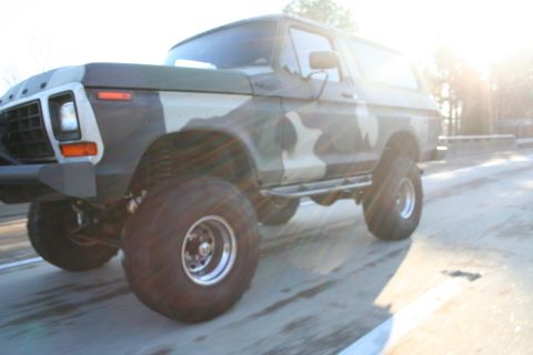1982 Ford Bronco - A lifted Ford Bronco with a camouflage paint job is seen driving on a highway.