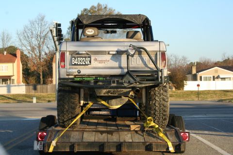 1982 Ford Bronco - A modified Ford Bronco is transported on a trailer, its rear end prominently displayed with custom modifications.