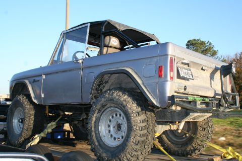 1982 Ford Bronco - This lifted Ford Bronco is secured to a trailer with yellow straps, ready for transport.