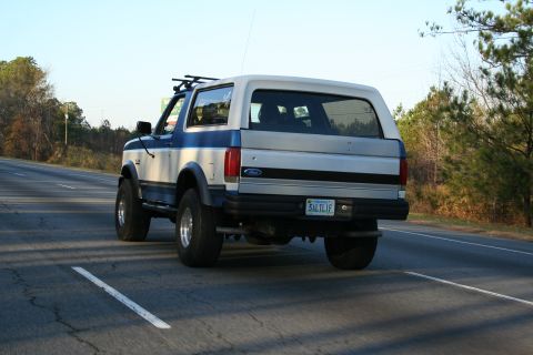 1982 Ford Bronco - A two-tone blue and silver Ford Bronco is seen from the rear driving on a highway.