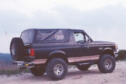 1988 Ford Bronco - This lifted Ford Bronco features a removable soft top and a spare tire mounted on the rear tailgate.