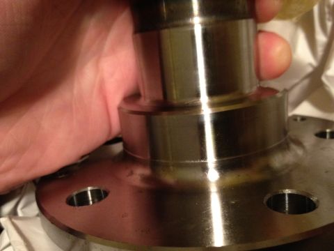 1996 Ford Bronco - A hand holds a metal wheel hub assembly, showing its machined surfaces and bolt holes. The 'SUPERMOTORS' watermark is visible.