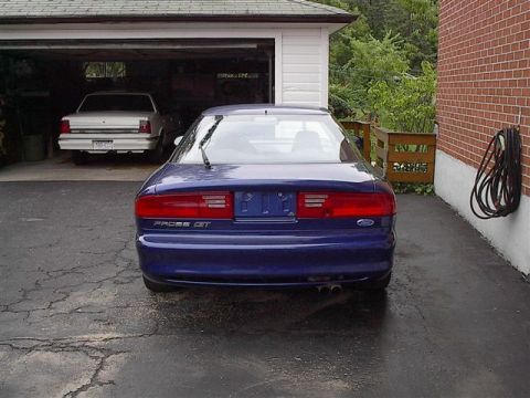 1993 Ford Probe - The rear of a blue 1993 Ford Probe GT is visible, with another white car in the garage behind it.
