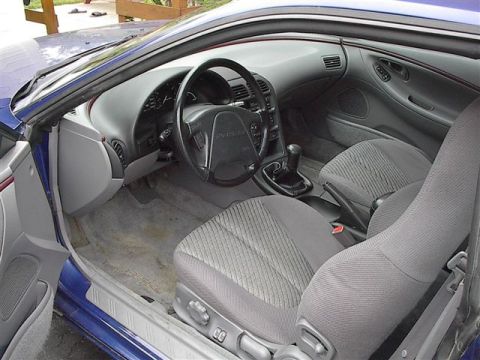 1993 Ford Probe - The interior of a 1993 Ford Probe, its dashboard, steering wheel, and patterned seats.