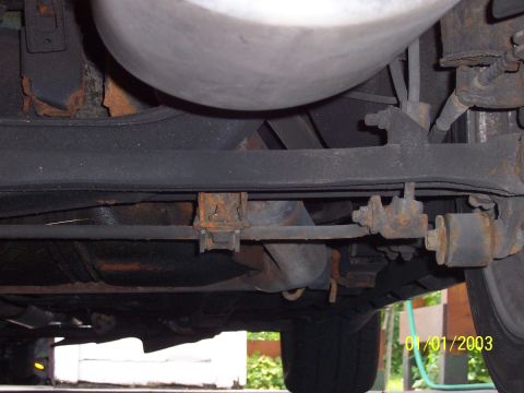 1993 Ford Probe - The underside of a vehicle, suspension components and a large muffler, with visible signs of rust.