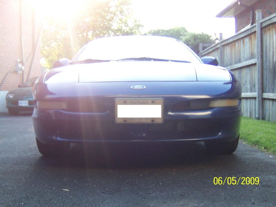 Blue 1993 Ford Probe front view, license plate obscured, parked on asphalt driveway