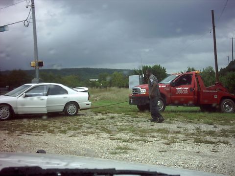 1996 Ford Bronco - A tow truck is pulling a white sedan, with a person standing between them.