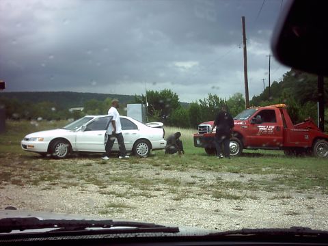 1996 Ford Bronco - A tow truck is present at a scene with a white sedan and several individuals.