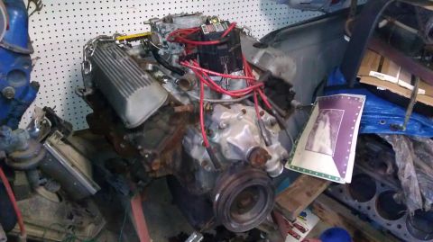 1989 Ford Bronco - A V8 engine is the main focus, surrounded by various car parts and stored items in a garage.