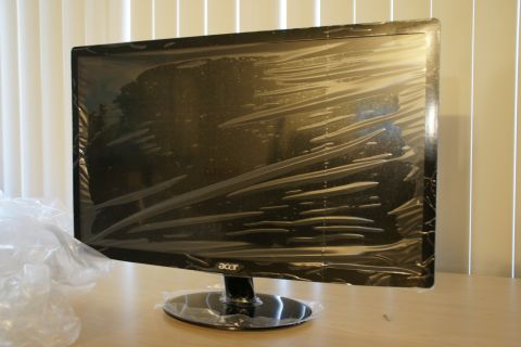 1993 Ford Taurus - A black Acer computer monitor, still in its protective plastic wrapping, sits on a desk in front of vertical blinds.
