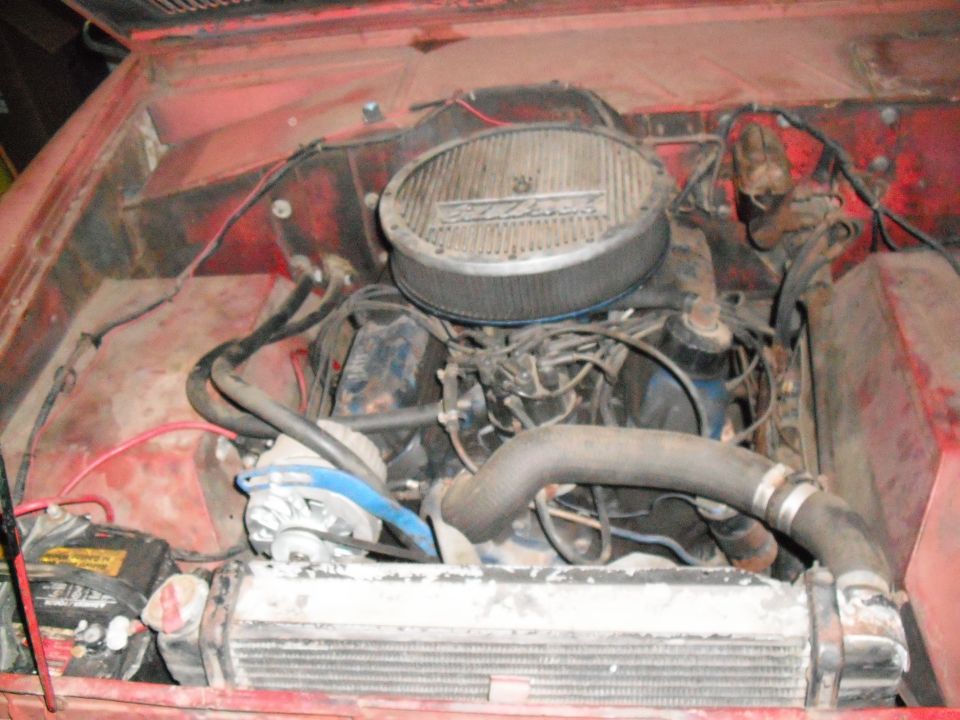 Engine bay with V8 engine, air cleaner, radiator, and battery visible